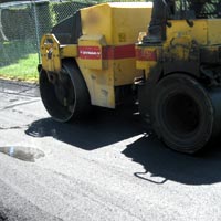 Compacting asphalt parking lot with roller